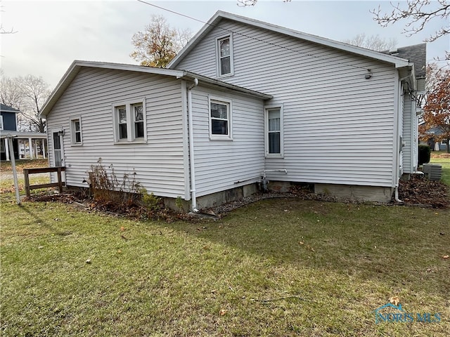 rear view of property featuring central AC and a lawn