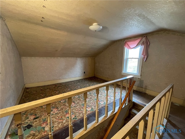 additional living space featuring a textured ceiling and lofted ceiling