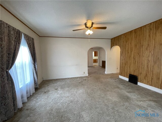 spare room featuring ceiling fan, a textured ceiling, and wooden walls