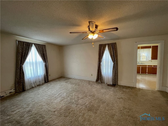 empty room with carpet, ceiling fan, and a textured ceiling