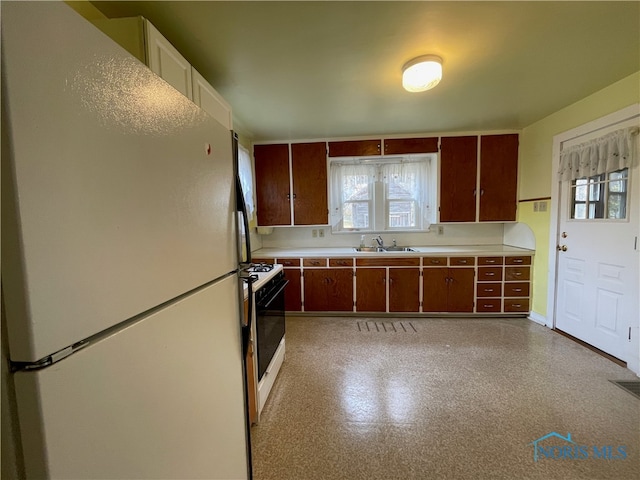 kitchen featuring dark brown cabinetry, white appliances, plenty of natural light, and sink