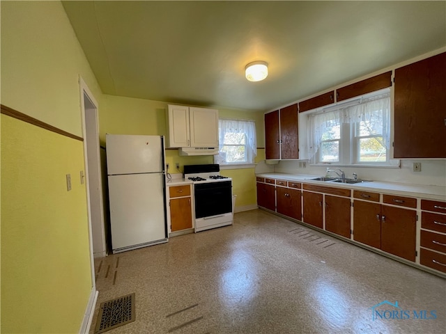 kitchen with white appliances, dark brown cabinetry, and sink