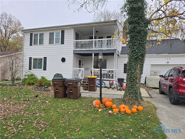 view of front property featuring a balcony, a garage, and a front lawn