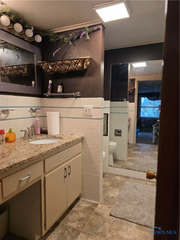 bathroom featuring vanity, toilet, and tile walls