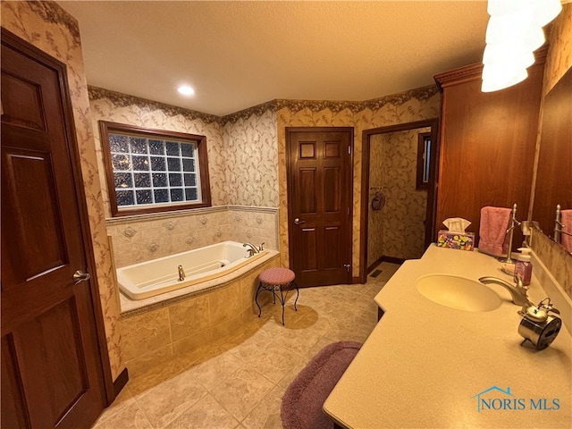 bathroom featuring vanity, a textured ceiling, a relaxing tiled tub, and tile patterned floors