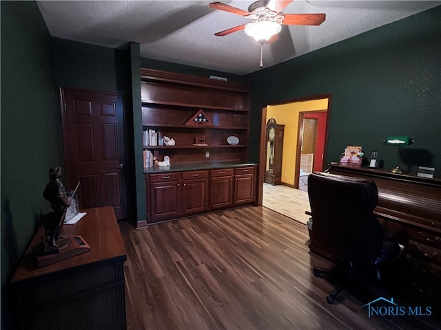 home office featuring ceiling fan, dark hardwood / wood-style flooring, and a textured ceiling