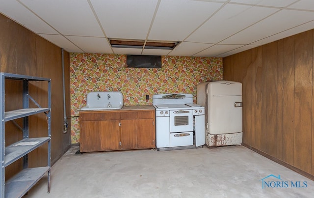 kitchen with a drop ceiling, wooden walls, and white stove