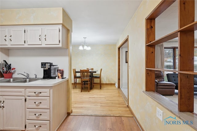 kitchen with sink, a chandelier, decorative light fixtures, and light wood-type flooring