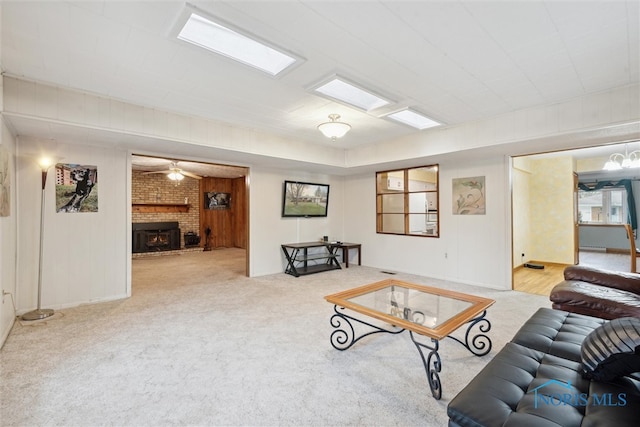 carpeted living room featuring a brick fireplace and ceiling fan