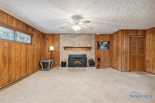 unfurnished living room with carpet flooring, ceiling fan, wood walls, and a baseboard radiator