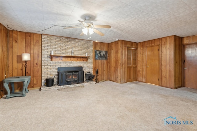 living room featuring a wood stove, wood walls, and light carpet