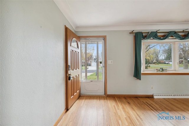 foyer featuring hardwood / wood-style flooring, baseboard heating, and a healthy amount of sunlight