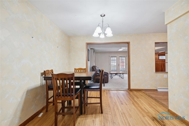 dining room featuring hardwood / wood-style floors, a baseboard heating unit, and a chandelier