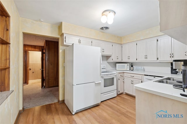 kitchen featuring white appliances, light hardwood / wood-style floors, white cabinetry, and sink