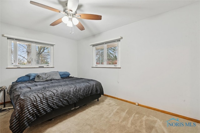 carpeted bedroom featuring multiple windows and ceiling fan