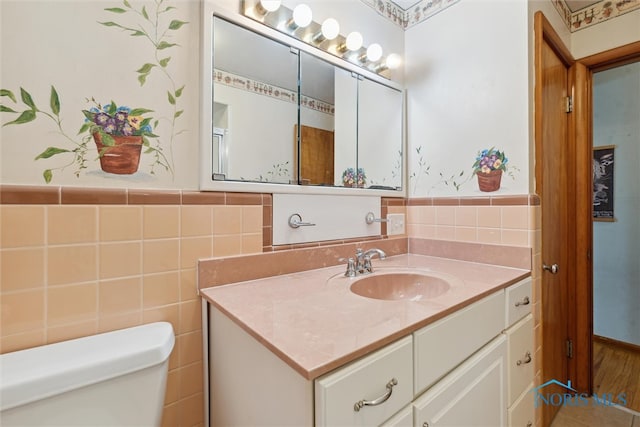 bathroom featuring vanity, toilet, and tile walls