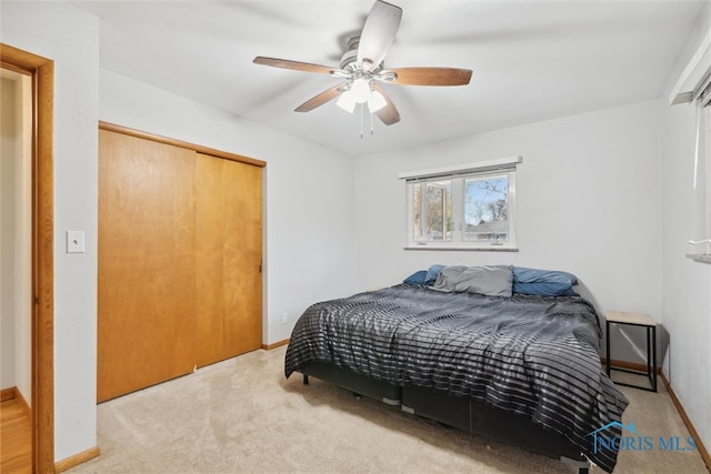 carpeted bedroom with ceiling fan and a closet