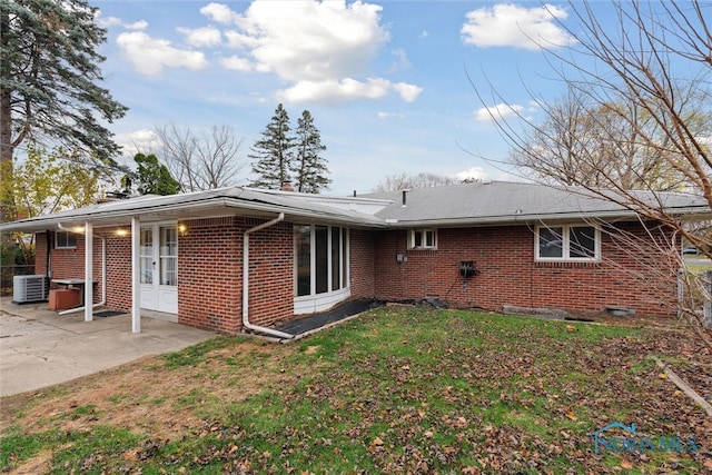 back of property with a lawn, central AC unit, and a patio area