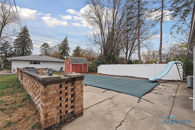 view of pool featuring a storage shed, a patio area, and a water slide