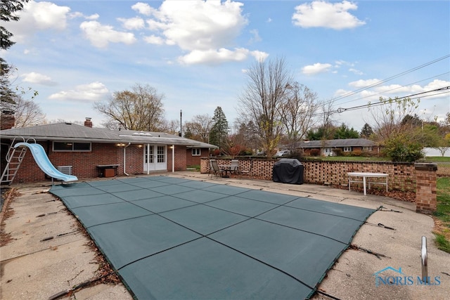 view of pool featuring french doors, grilling area, a patio area, and a water slide