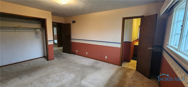 unfurnished bedroom featuring light carpet and a closet