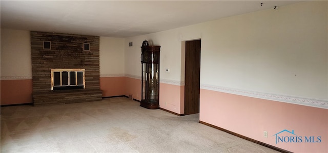 unfurnished living room featuring light carpet and a fireplace