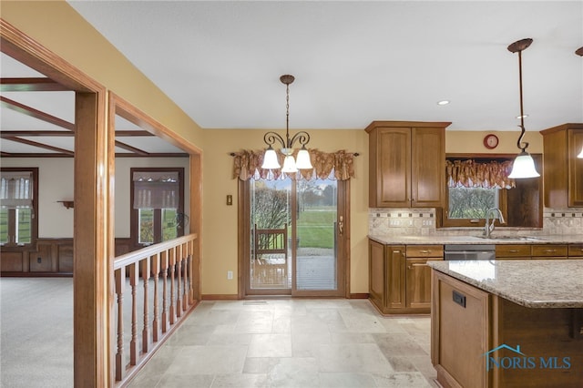 kitchen featuring decorative light fixtures, dishwasher, backsplash, and a chandelier