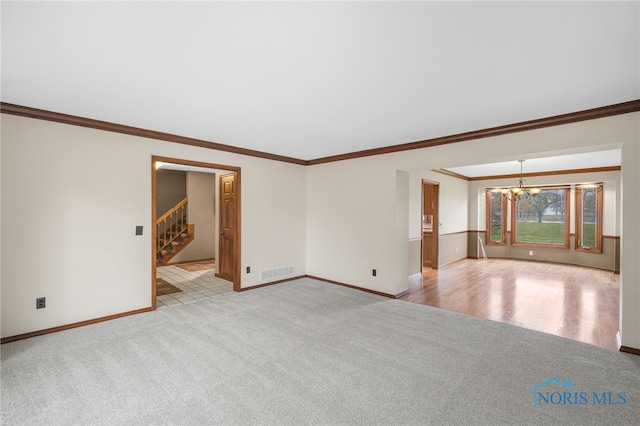 spare room featuring a notable chandelier, ornamental molding, and light carpet