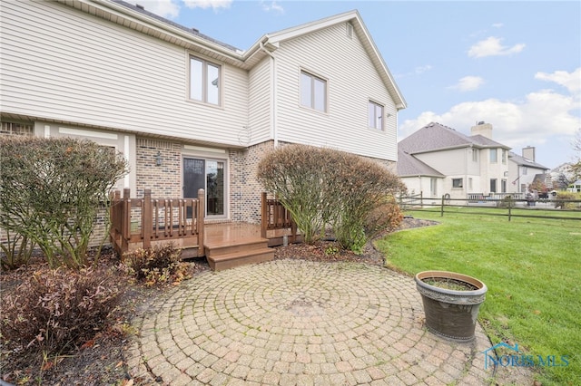 rear view of house with a lawn, a wooden deck, and a patio