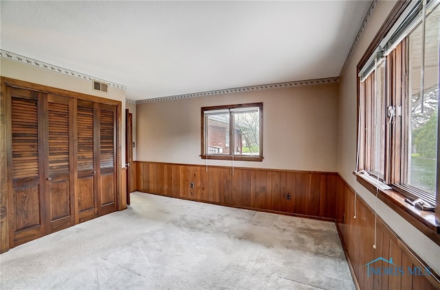 unfurnished bedroom with wooden walls, a closet, and light colored carpet