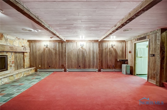 basement featuring white fridge, a stone fireplace, light colored carpet, and wooden walls