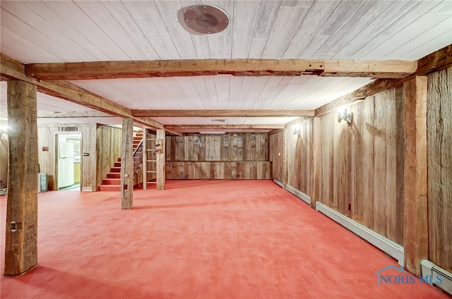 basement with baseboard heating, wood walls, carpet flooring, and white refrigerator