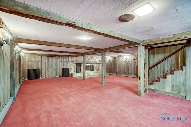 basement featuring a baseboard heating unit, carpet floors, and wooden walls