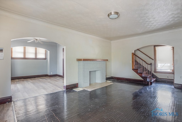 unfurnished living room featuring ornamental molding, a textured ceiling, ceiling fan, wood-type flooring, and a fireplace