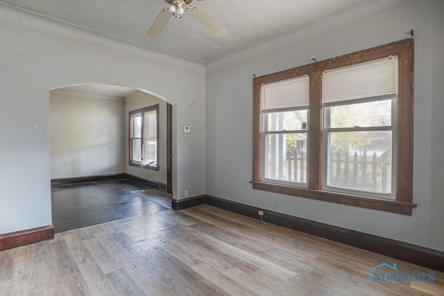 empty room featuring a wealth of natural light, ceiling fan, ornamental molding, and hardwood / wood-style flooring