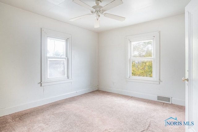 carpeted spare room with ceiling fan and plenty of natural light