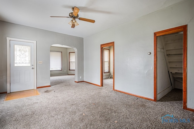 interior space with carpet flooring, a walk in closet, a closet, and ceiling fan