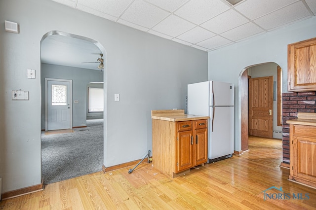 kitchen with ceiling fan, a drop ceiling, light hardwood / wood-style floors, and white refrigerator