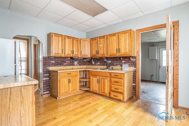 kitchen with white refrigerator, light hardwood / wood-style floors, a drop ceiling, and sink