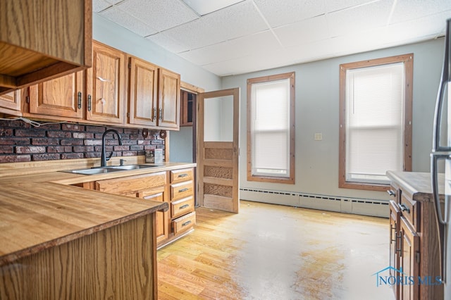 kitchen featuring a paneled ceiling, wood counters, a baseboard heating unit, sink, and light wood-type flooring