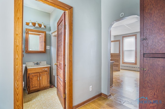 corridor featuring a baseboard radiator, light hardwood / wood-style flooring, and sink