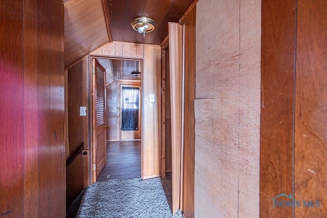 corridor featuring dark hardwood / wood-style floors, wooden ceiling, wooden walls, and vaulted ceiling