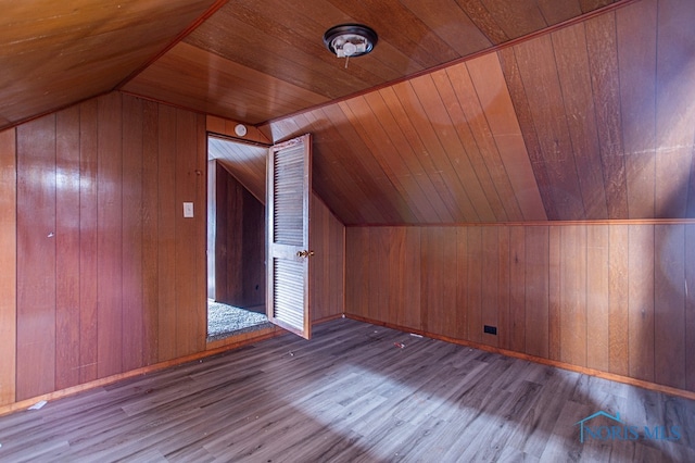 additional living space with light wood-type flooring, wooden walls, and wooden ceiling