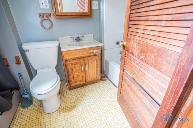 bathroom featuring a tub to relax in, vanity, and toilet