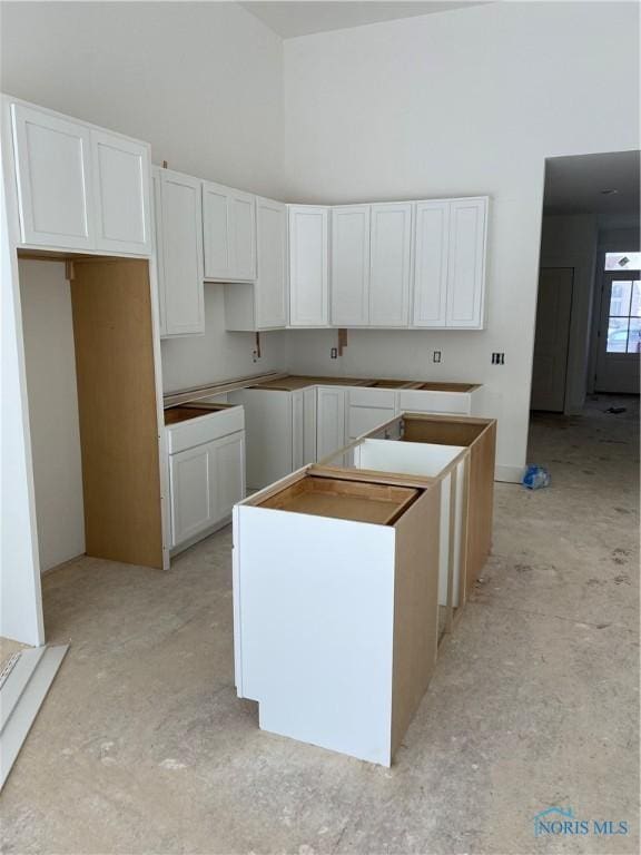 kitchen with white cabinetry, a kitchen island, and a high ceiling