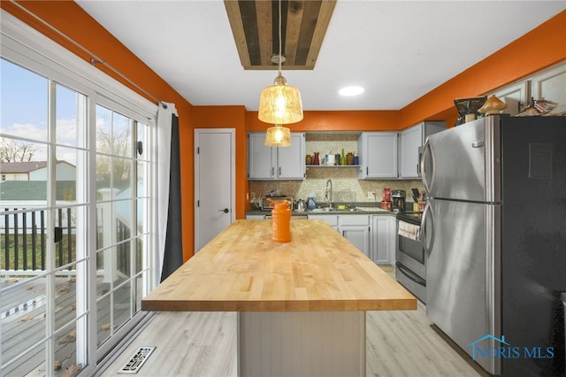 kitchen featuring stainless steel appliances, decorative light fixtures, gray cabinets, decorative backsplash, and a kitchen island