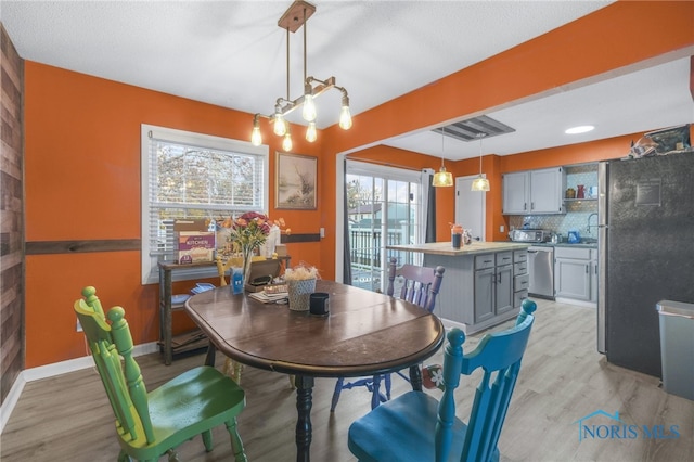 dining room with a chandelier, light wood-type flooring, and a wealth of natural light