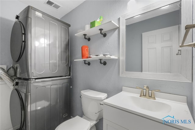 bathroom with stacked washer and dryer, vanity, and toilet