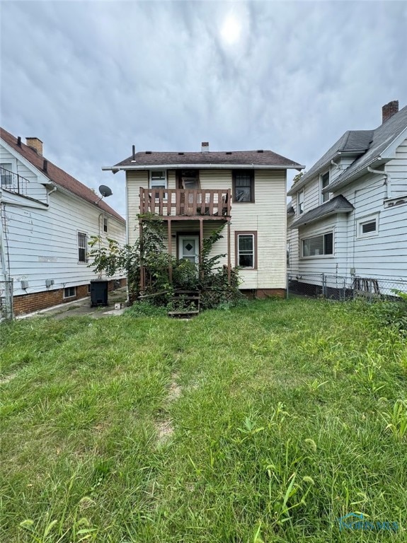 rear view of property with a lawn and a balcony