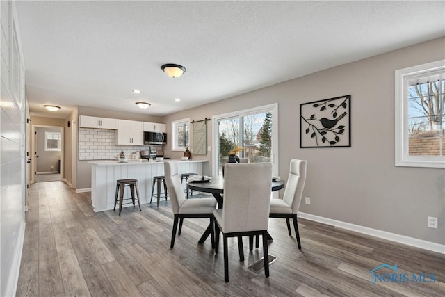 dining area with light hardwood / wood-style flooring and a textured ceiling